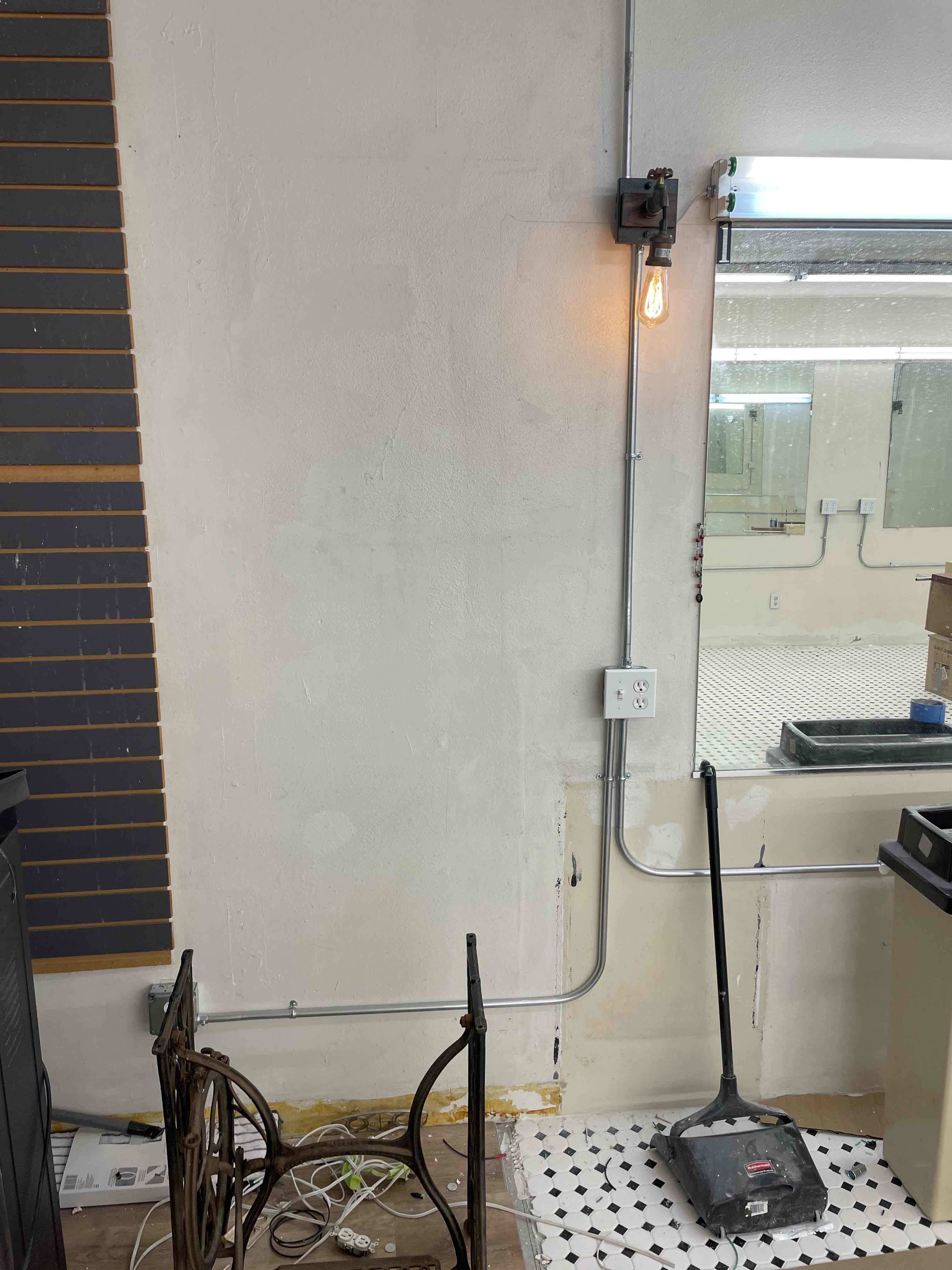 Wall sconce, receptacle, and surface conduit photographed during documented AWC electrical work